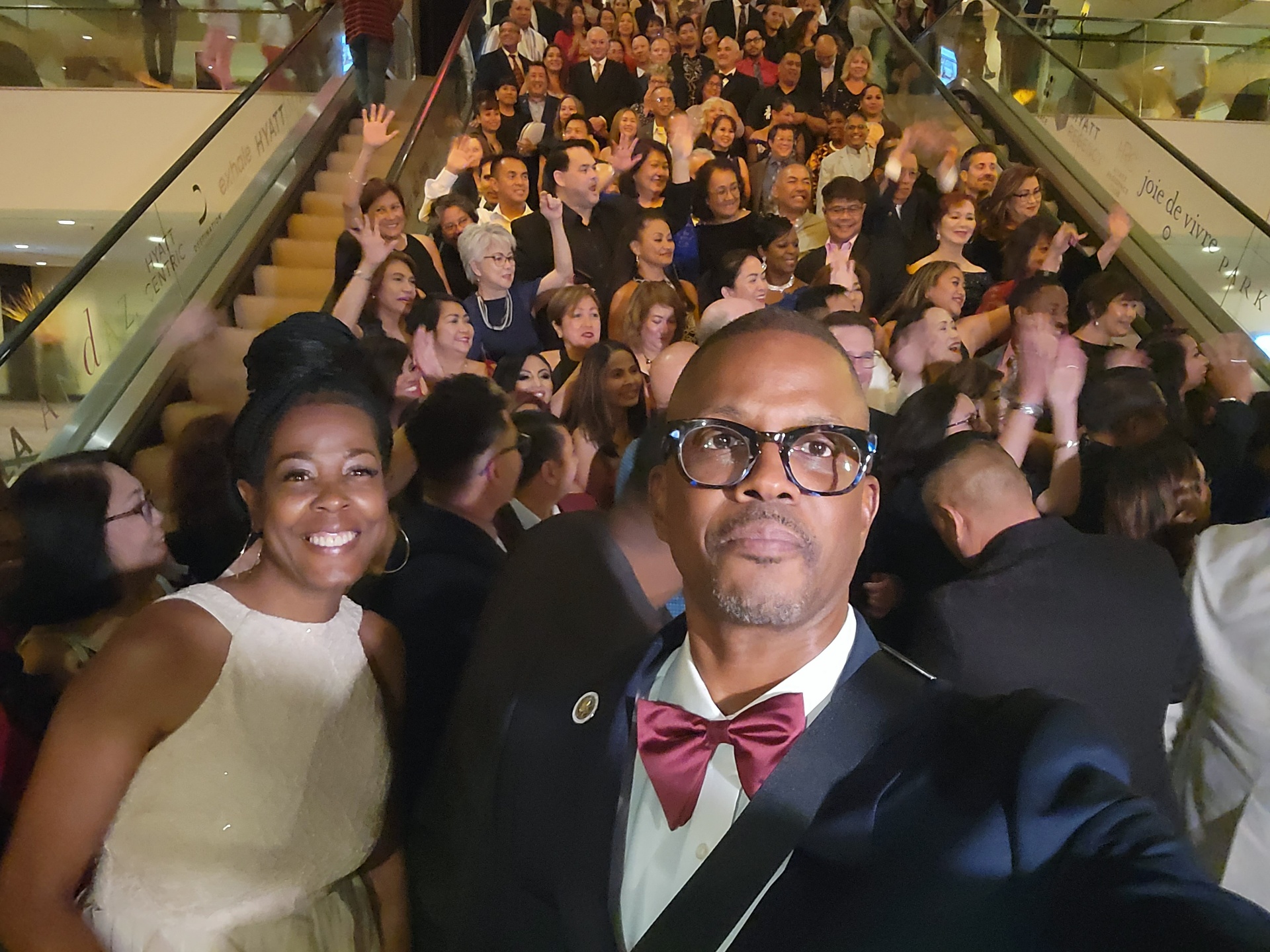Corey Artis and his wife at the FinFit Life annual recognition gala with the full company gathered on the grand staircase behind them